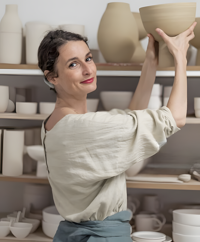 Young spanish woman placing a big ceramic bowl onto a shelf full of ceramics