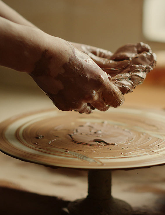 A ball og clay being placed onto a throwing wheel