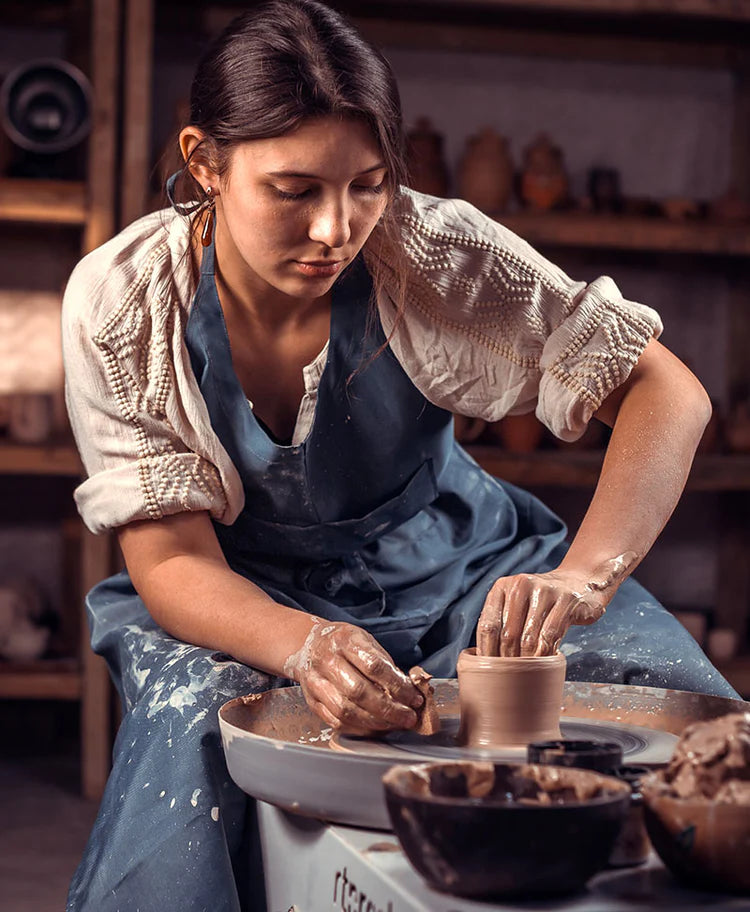 Young scandinavian woman shaping a clay cup on the throwing wheel