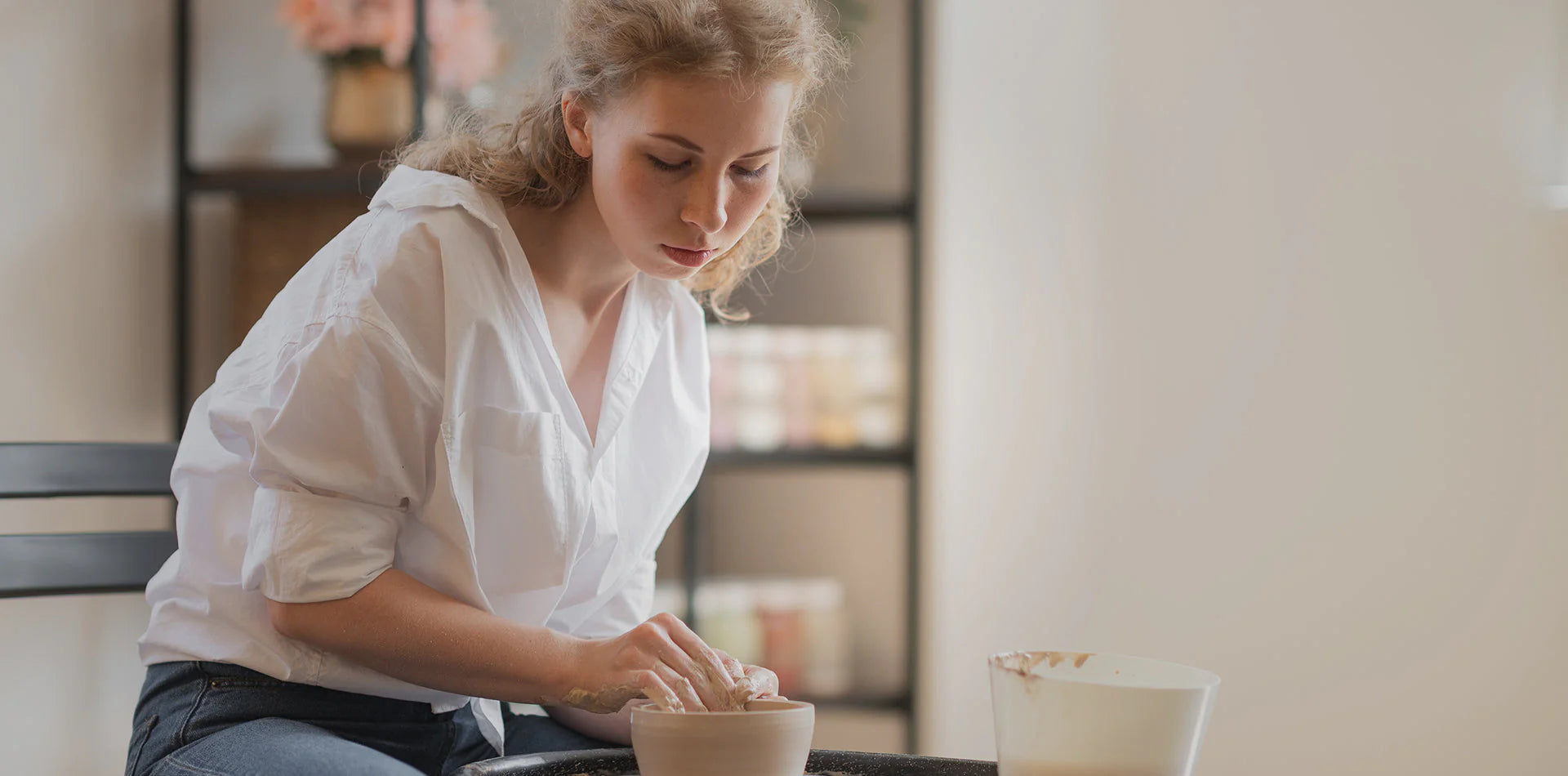 Young woman in ceramics studio shaping a clay bowl